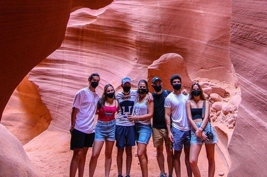 A group of people standing in a narrow canyon with red rock walls. 1