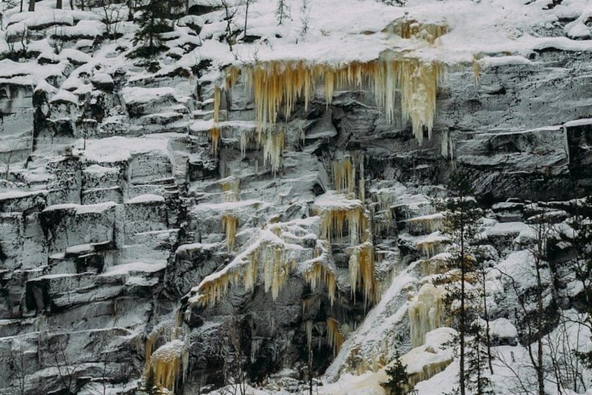 Un paysage enneigé, avec des glaçons pendants d’une falaise rocheuse. 4