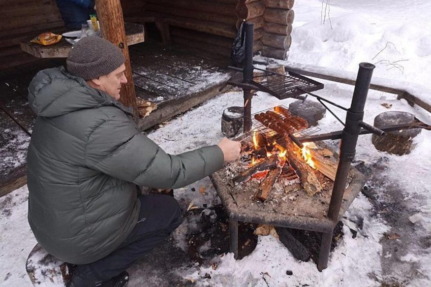 Une personne qui fait griller des saucisses à l’extérieur, dans un environnement enneigé. 3