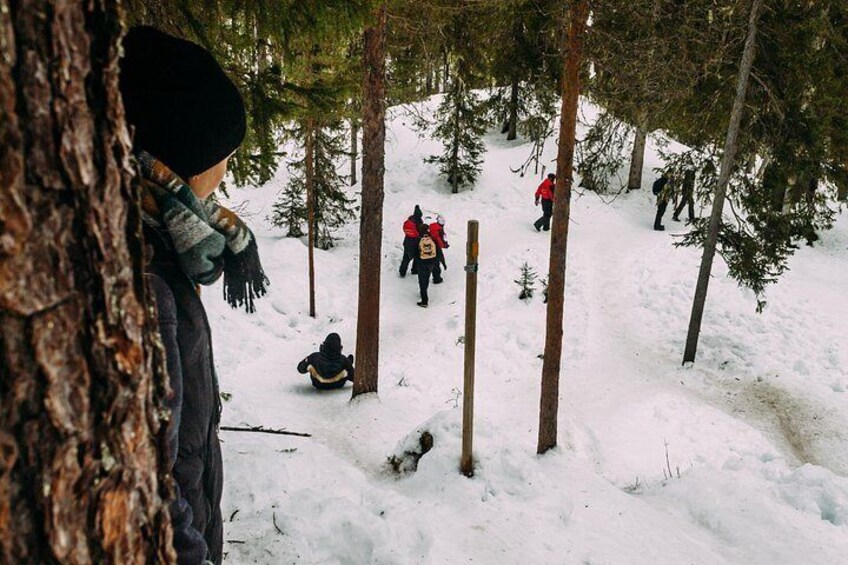A snowy forest with people hiking and a person sitting on the ground. 5