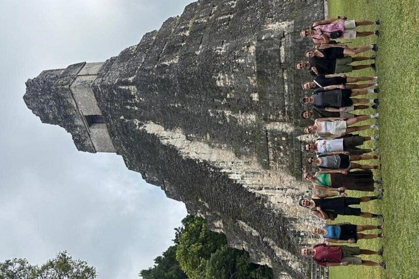 A group of people standing in front of a large ancient stone structure. 5