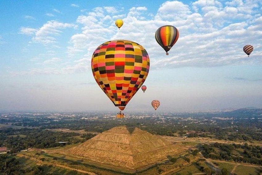 A landscape with hot air balloons in the sky. 5
