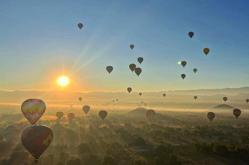 Hot air balloons over a landscape with the sun in the background. 2