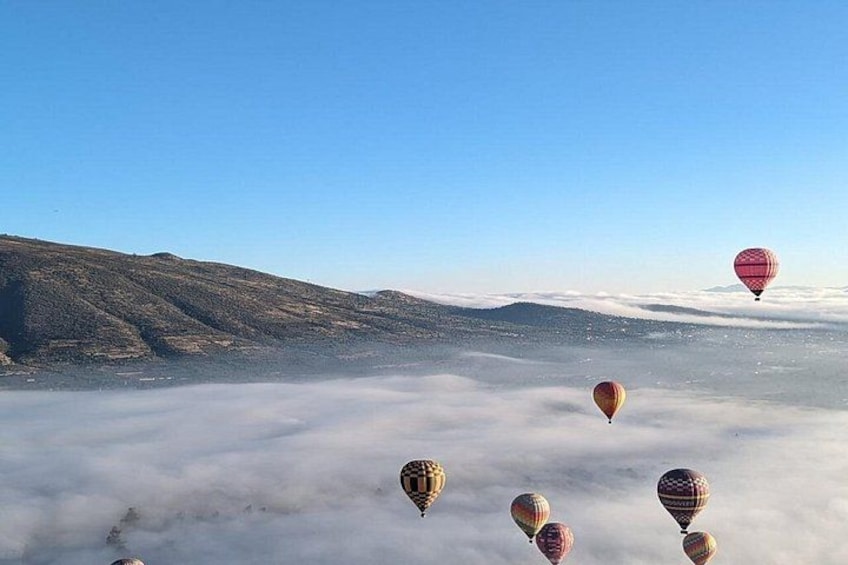 Hot air balloons floating above a cloud-covered landscape. 3