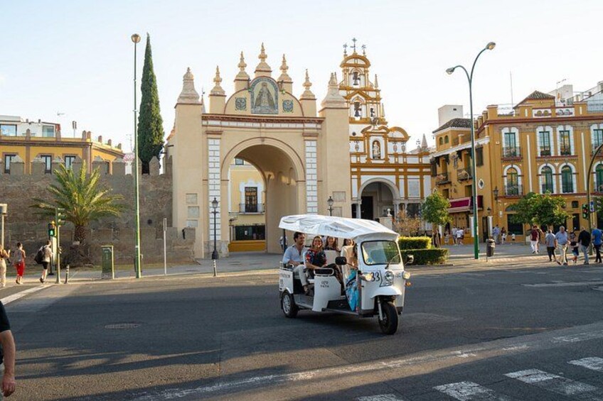A vintage car with passengers, a historic archway, and a busy street with pedestrians. 4