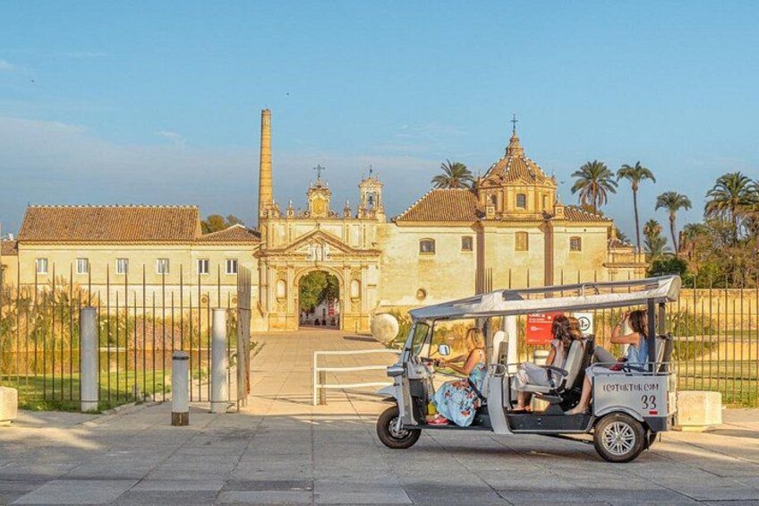En tuk-tuk holder parkeret foran en historisk bygning med en stor buegang og et kirketårn. 5