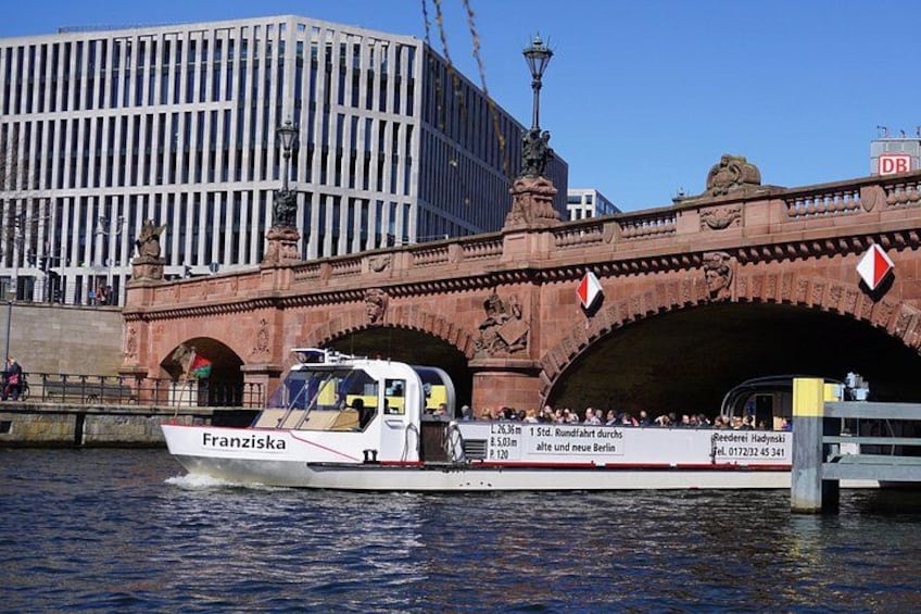 A boat named Franziska passing under a bridge with a modern building in the background. 3