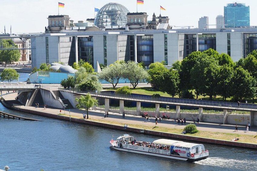 A river with a boat, a bridge, and a modern building with flags. 2