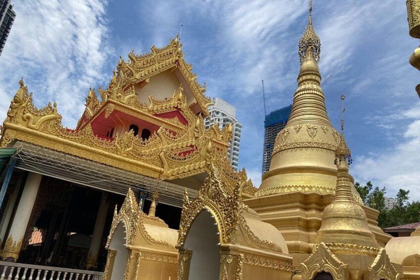 Et gyldent tempel med detaljeret arkitektur, en stor stupa og en moderne bygning i baggrunden. 3