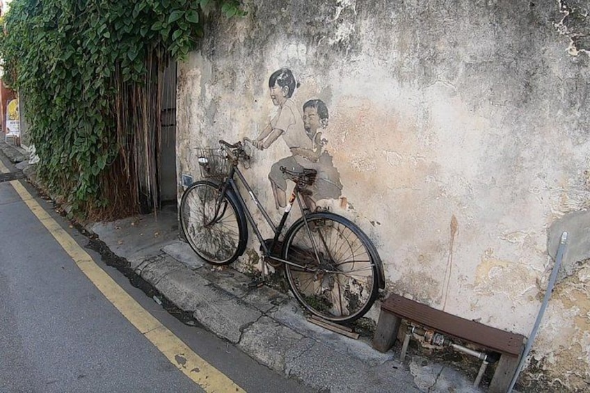 En cykel lænet op ad en væg med et muralmaleri af en cyklist. 2