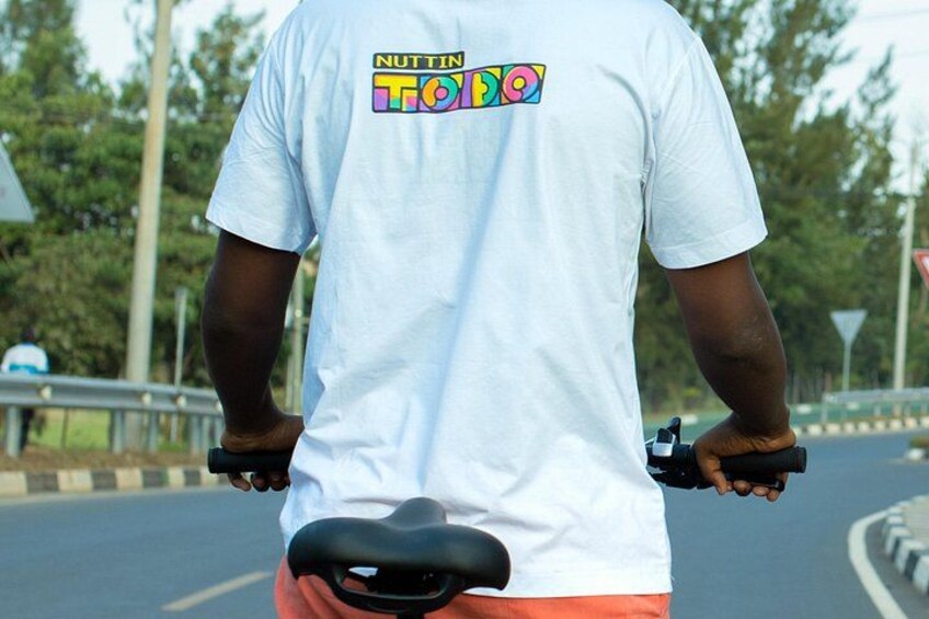 En person som kör motorcykel på en väg, iförd en vit t-shirt och orange byxor. 5