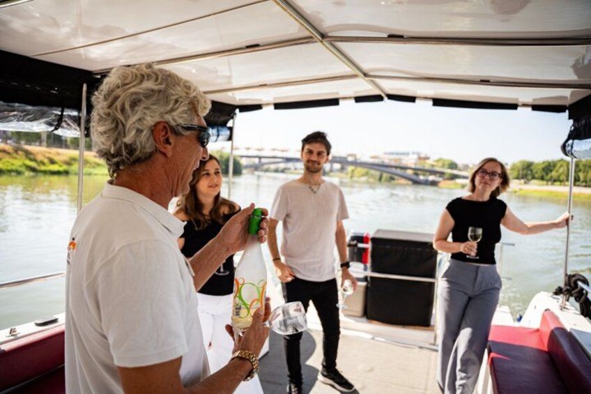 A group of people on a boat with a river and a bridge in the background. 5
