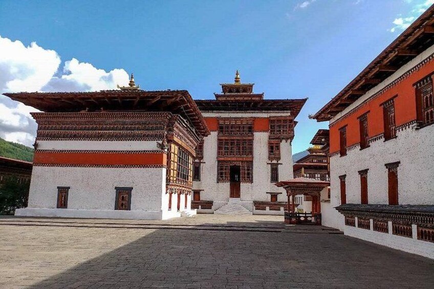 A traditional Tibetan building with a red and white facade, a central spire, and a courtyard. 2