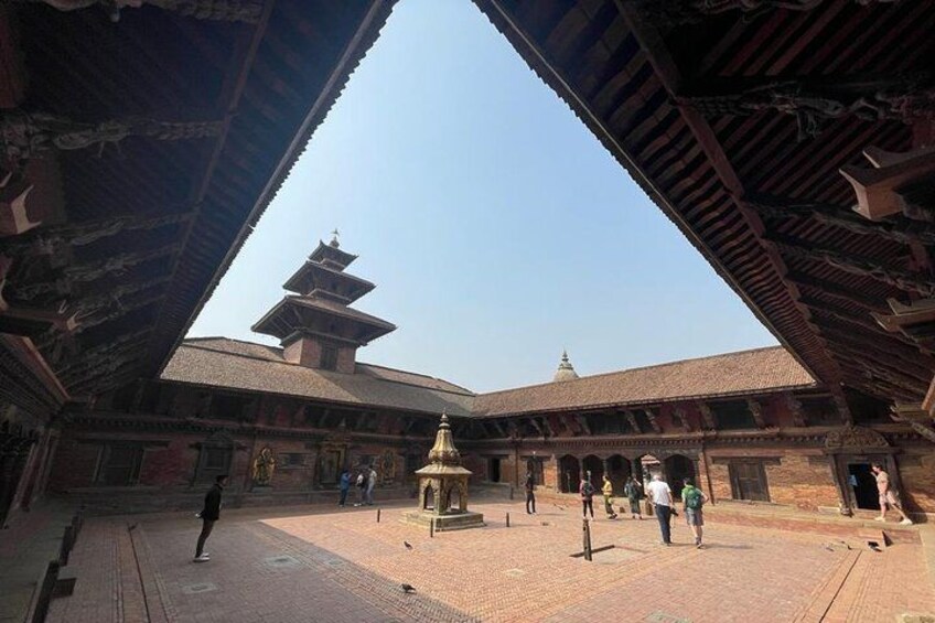 A traditional building with a central golden stupa, a pagoda-like structure, and a brick courtyard. 2