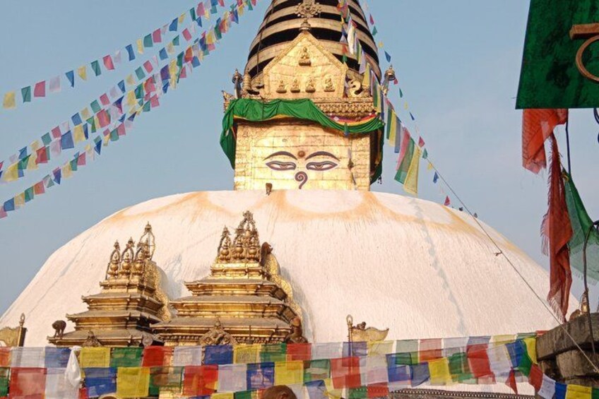 A large white stupa with golden structures and flags. 4
