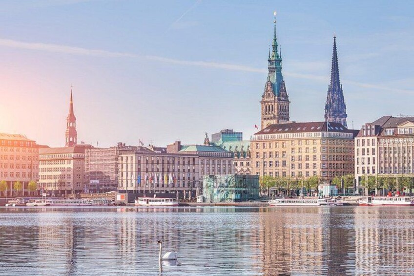 A cityscape with a river, a swan, and prominent buildings including a church with a tall spire. 1