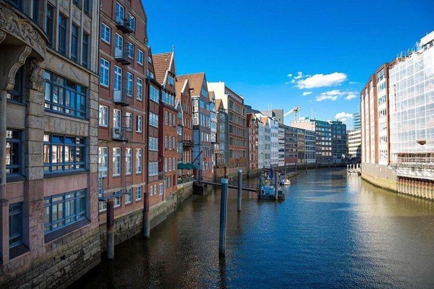 A canal with buildings on one side and a bridge in the distance. 3