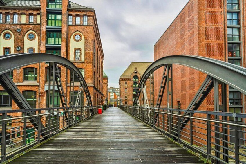 A pedestrian bridge with metal arches, connecting two buildings with brick facades. 4