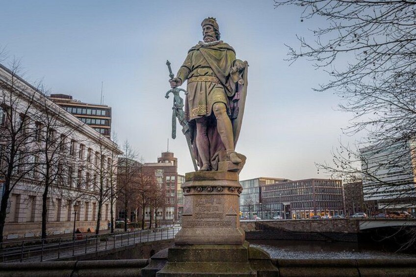A statue of a historical figure in a city square surrounded by modern buildings. 2