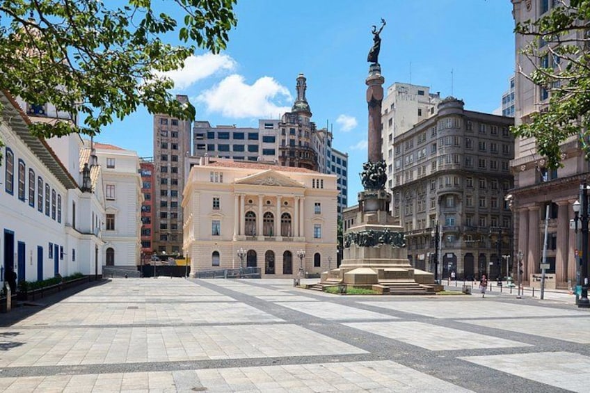 A plaza with a fountain, a statue, and historic buildings. 2