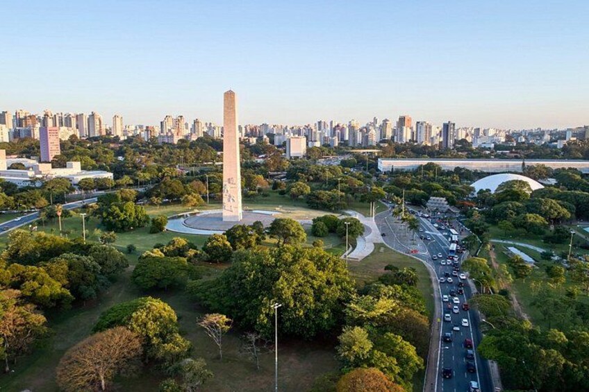 A cityscape with a prominent obelisk, surrounded by greenery and a busy road. 5