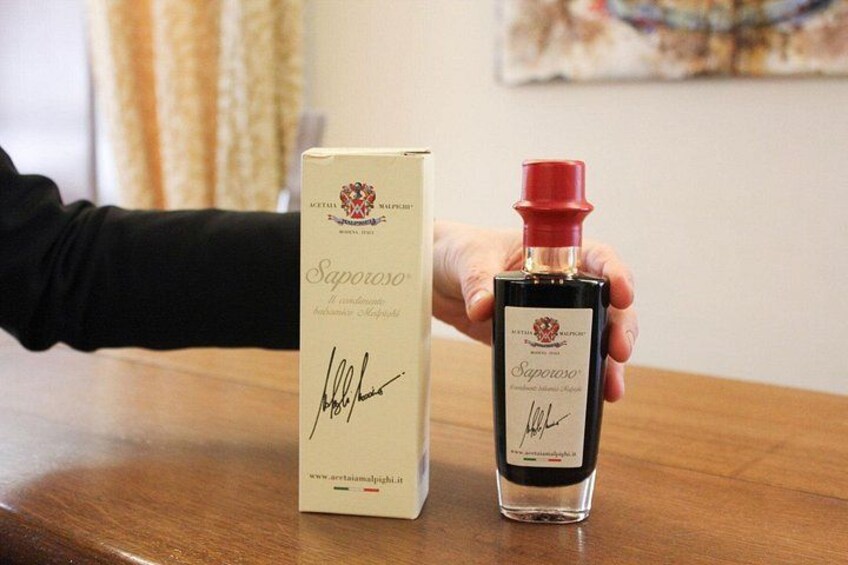Una bottiglia di vino Saporoso e la sua scatola su un tavolo di legno. 1