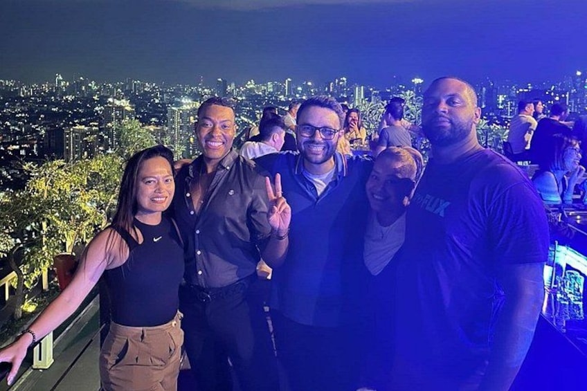 Un grupo de personas posando en una azotea con un paisaje urbano de fondo. 5