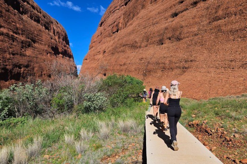 Un groupe de personnes se promène sur une promenade en bois qui traverse un canyon aux parois rocheuses rouges. 4