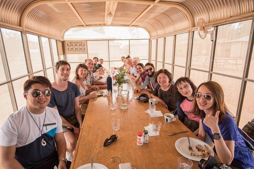 Een groep mensen dineert in een houten boot met grote ramen. 5