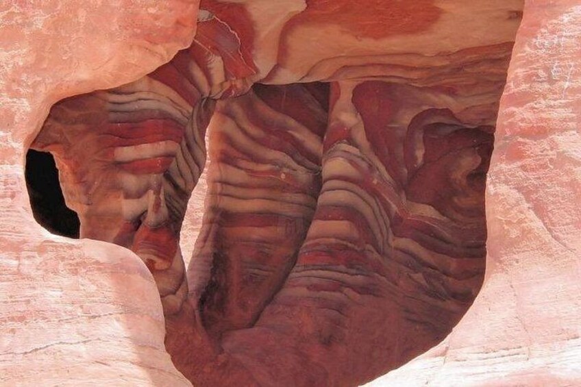 A rock formation with layered patterns and a cave entrance. 4