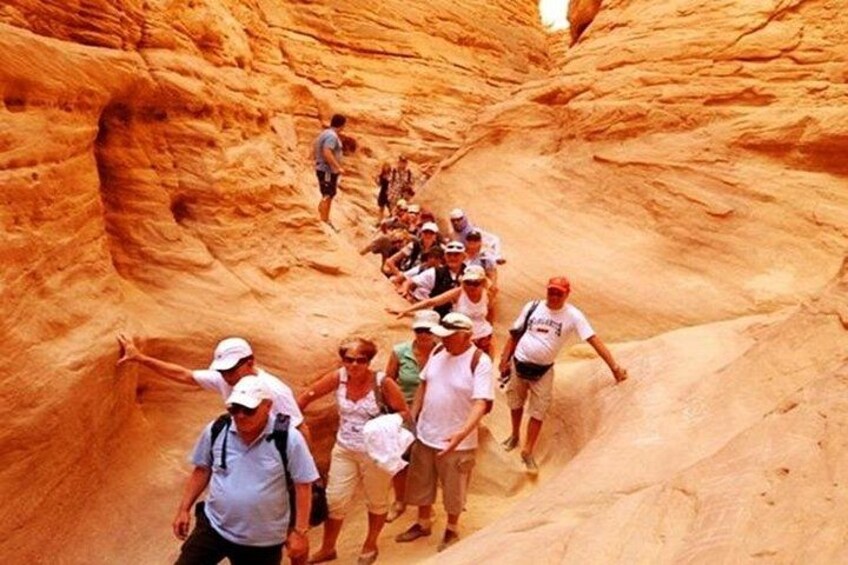 A group of people hiking through a narrow canyon with steep walls. 1