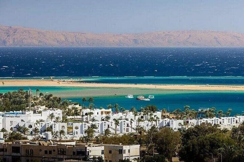 A coastal town with white buildings, a beach, and boats on the water. 2