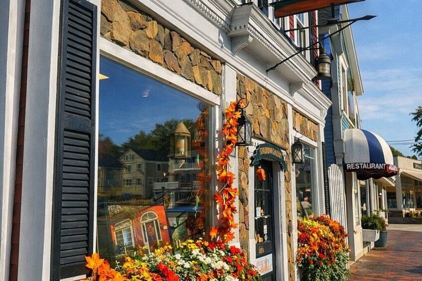 A restaurant with a stone facade, large windows, and outdoor flowers. 4