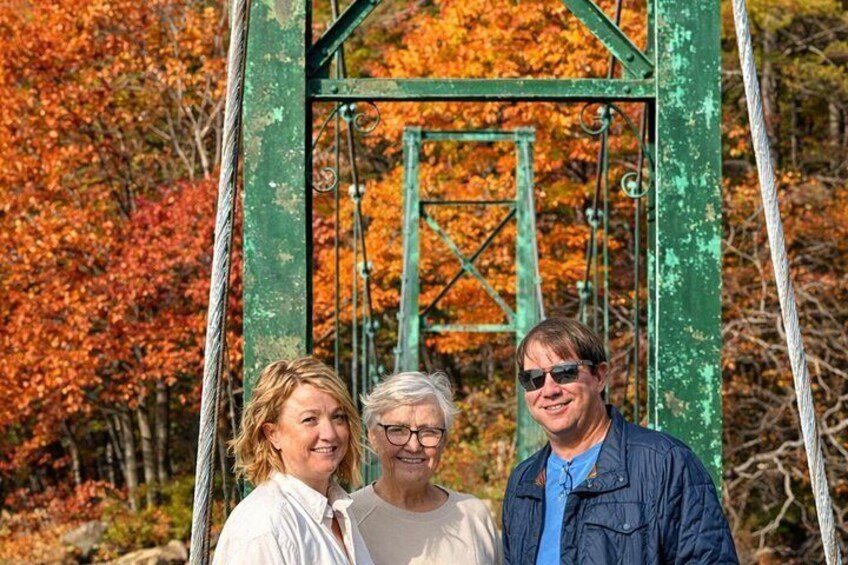 Three people standing in front of a green metal structure with a rope. 2