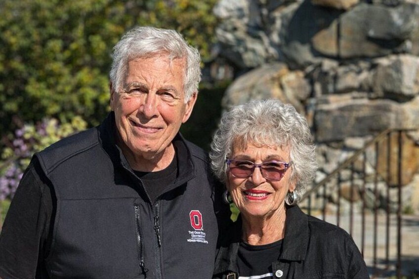 Two people standing in front of a rocky background with greenery. 3