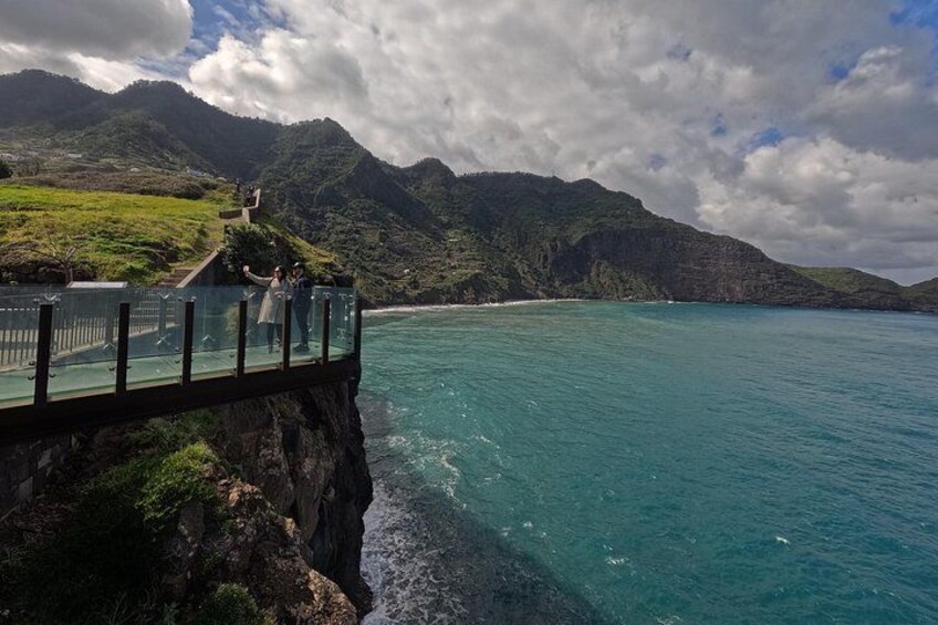 A glass bridge over a body of water, with mountains in the background. 5