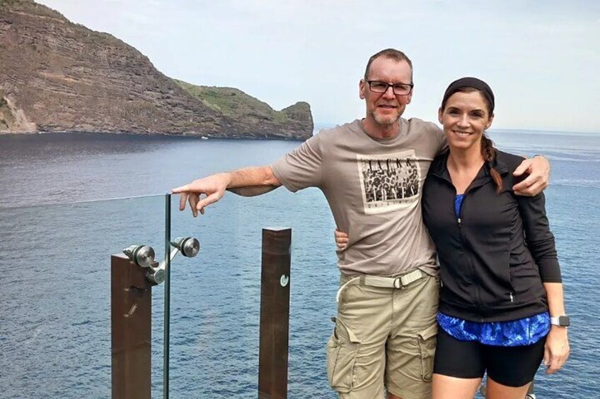 A man and woman standing by a dock with a rocky coastline in the background. 3
