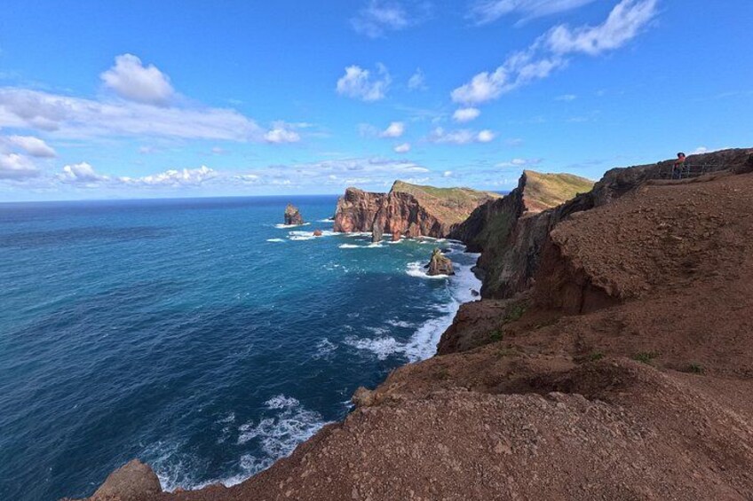 A coastal landscape with cliffs, a rocky outcrop, and the ocean. 2