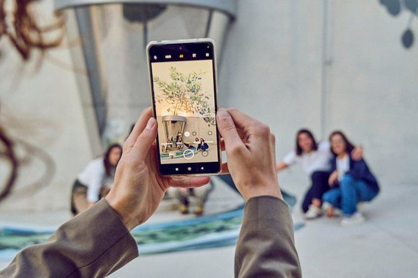 A person holding a smartphone with a photo of a group of people sitting on a bench. 4
