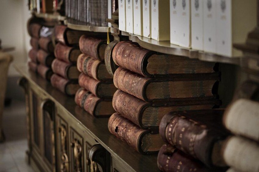 A collection of old books and binders on a wooden shelf. 2