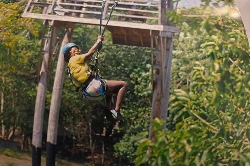 A person zip-lining through a forested area with wooden structures. 2