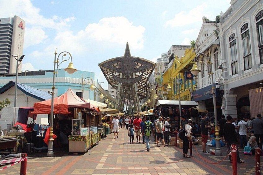 A bustling street with market stalls, a distinctive metal structure, and historic buildings. 5