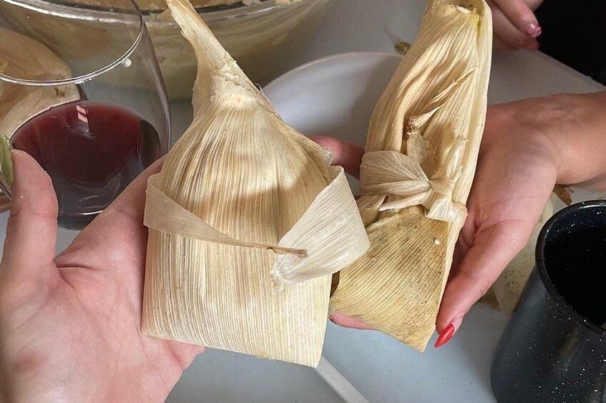 Hände halten Tamales, eingewickelt in Maisblätter. 2