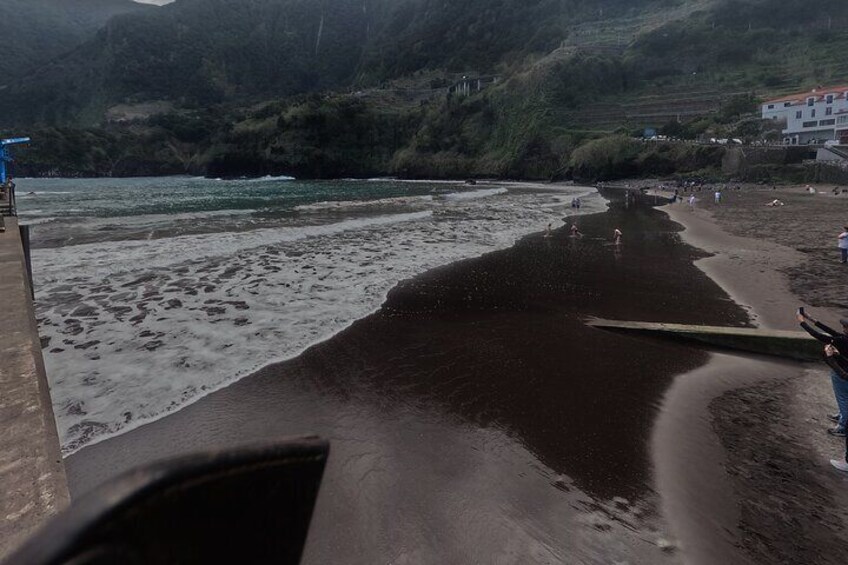 A beach with waves, a wooden boardwalk, and people in the distance. 2