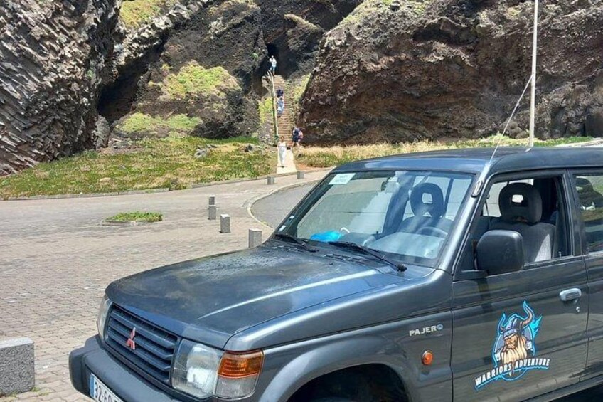 Un SUV de color oscuro estacionado cerca de un paisaje rocoso con un monumento al fondo. 5