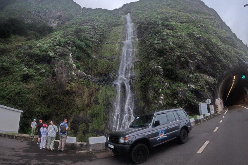 Ein Wasserfall, der Eingang eines Tunnels und ein Fahrzeug auf einer Straße. 2