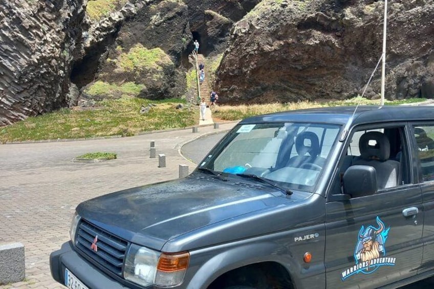 A dark-colored SUV parked near a rocky landscape with a monument in the background. 3