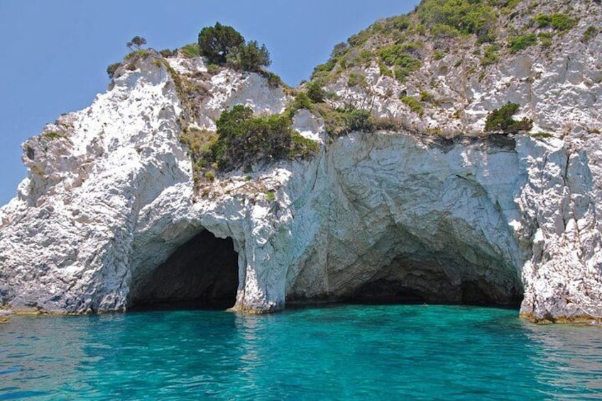 A white rock formation with a cave entrance and turquoise water. 2