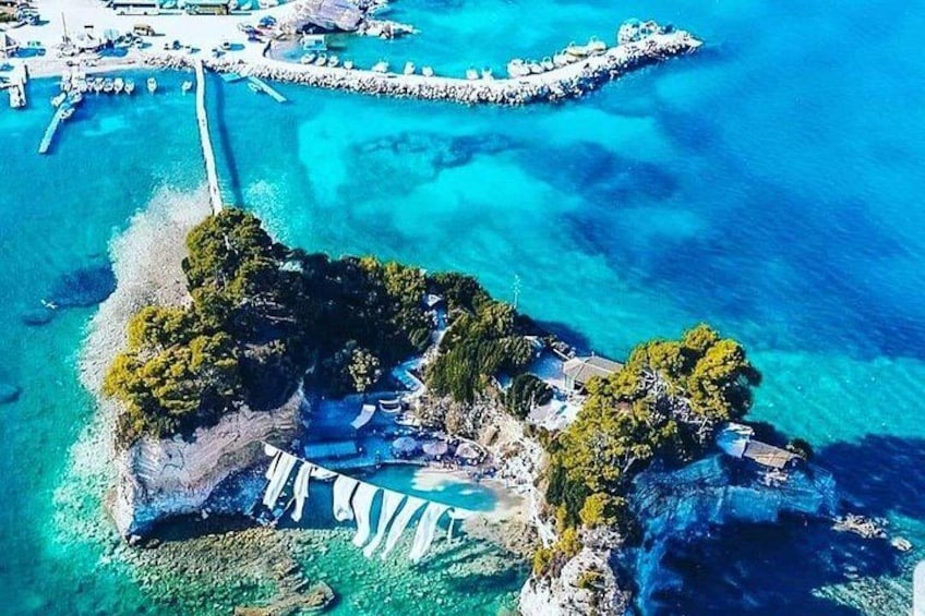 An aerial view of a coastal area with clear blue waters, a pier, and a small island with buildings and trees. 2