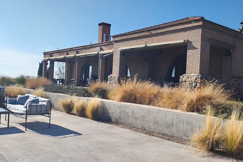 A brick building with a patio area, outdoor seating, and tall grasses. 5